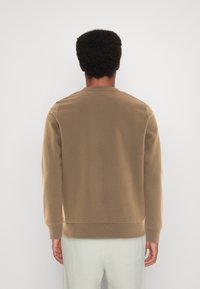 Sudadera marrón de cuello redondo con mangas largas, textura suave, puños y dobladillo acanalados, diseño liso, vista desde atrás.