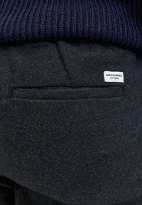 Temno sivi bombažni hlače z teksturiranim zaključkom, z majhno belo oznako z napisom "JACK & JONES" blizu zadnjega žepa.