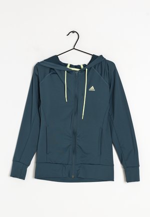 Chaqueta con capucha y cremallera en material azul verdoso oscuro con cordones amarillos y un pequeño logo en el lado izquierdo del pecho; cuenta con bolsillos laterales y puños acanalados.