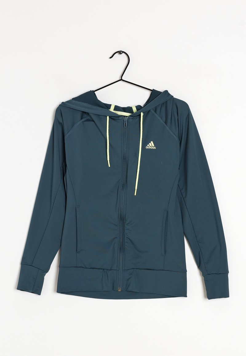 Kurtka z kapturem zapinana na zamek błyskawiczny w ciemnym morskim kolorze, z żółtymi troczkami i małym logo na lewej piersi; posiada boczne kieszenie i ściągacze na mankietach.