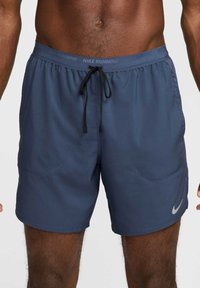 Pantalones cortos de running Nike en azul marino con cinturilla elástica, cordón interno y dos bolsillos laterales; presenta un pequeño logo plateado en el lateral.