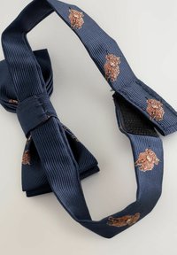 Tamsiai mėlynas peteliškė iš tekstūruotos ribuotos medžiagos, su išsiuvinėtais rudais Škotijos galvijų raštais ant juostos. Komplekte reguliuojamas užsegimas.