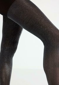 Sorte metalliske lårhøje strømpebukser med en glitrende finish, der har en glat tekstur og en sømløs design ved toppen og lårområdet.