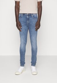 Jeans skinny de color azul claro con un lavado desgastado, diseño de cinco bolsillos y zapatillas blancas. Confeccionados en denim con ligero elasticidad para mayor comodidad.