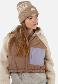 Braun gesteppte cropped Jacke mit leicht lila Tasche, ergänzt durch einen cremefarbenen Fleece-Kragen. Beigefarbener gestrickter Hut mit Schneeflockenmuster.