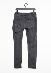 Jeans skinny de denim gris cuelgan de una percha negra, con una cintura alta, dos bolsillos traseros y una textura suave con un ligero brillo.