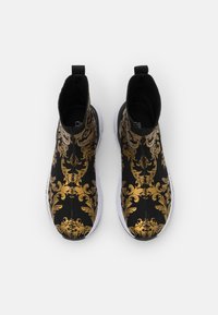 Černé a zlaté vzorované kotníkové boty se strečovým textilním svrškem, bílou podrážkou a poutky na každé patě pro snadné obouvání.