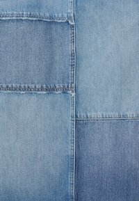 Foltos farmeranyag, amely különböző kék árnyalatokat tartalmaz, látható varratokkal összeillesztve, bemutatva a jellegzetes textúrákat és mintákat.