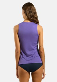 Purple tank top with a smooth texture, featuring a round neckline and wide armholes, paired with navy shorts.