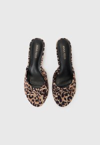 Leopard print slide sandals with a black inner lining and small bow detail on the front. Soft fabric material and open-toe design.