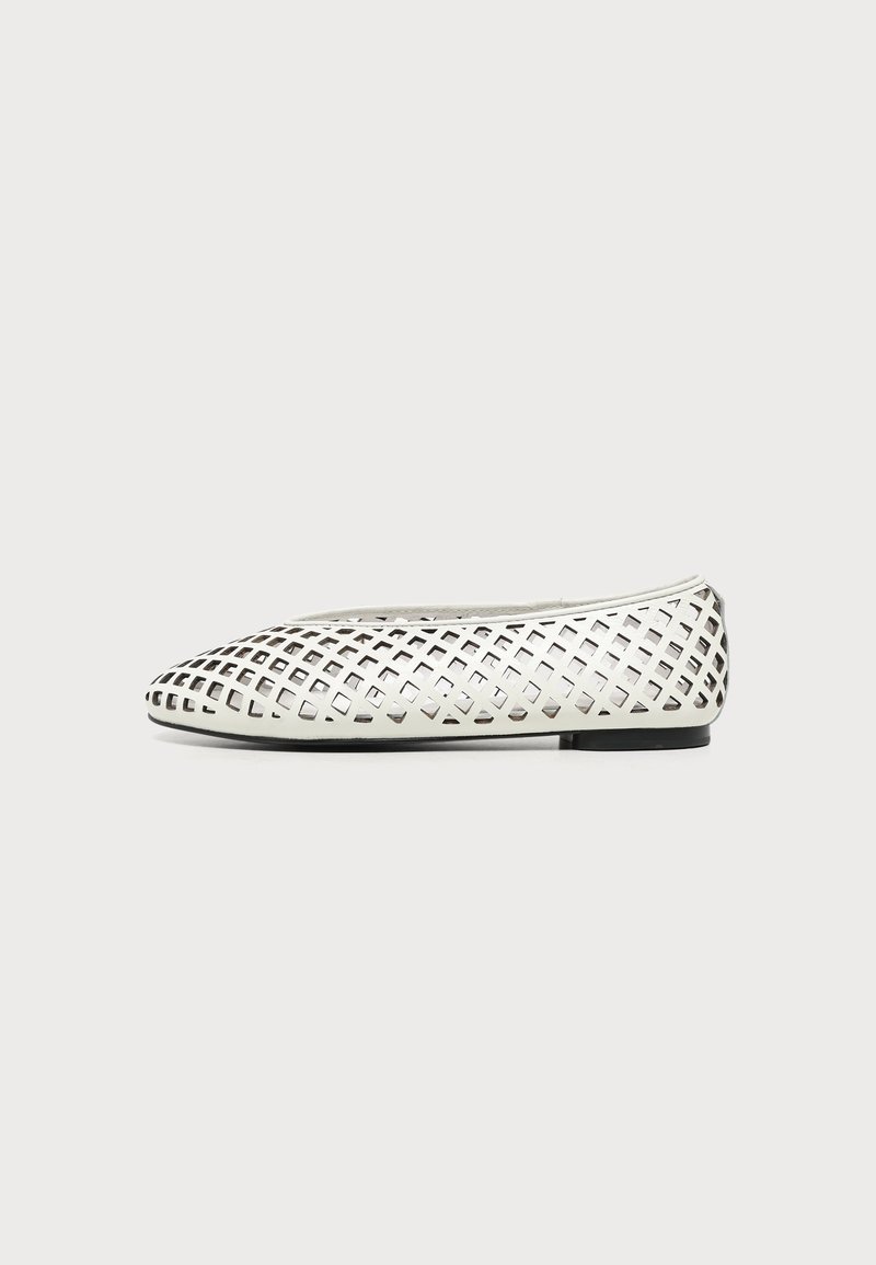 Chaussure plate blanche avec un motif en treillis de découpes en forme de losange et une semelle noire sur un fond uni.