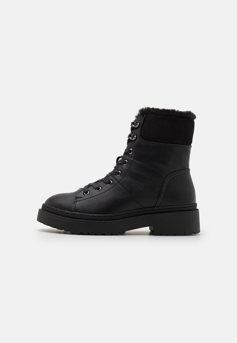 Black leather ankle boots with a textured upper, faux fur lining, round toe, and thick rubber sole. Features metal eyelets and laces.