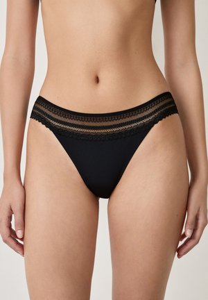 Black thong underwear made from smooth fabric. Features a decorative lace waistband with contrasting delicate stripes.