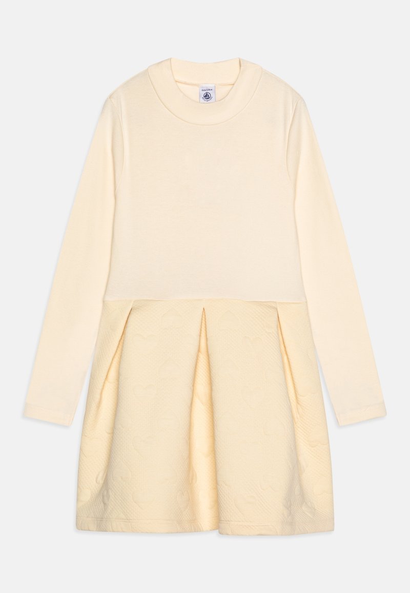 Robe à manches longues avec un haut beige clair et une partie inférieure plissée ornée d'un motif de cœurs texturé. Fabriquée en coton doux.