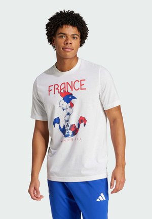 T-shirt en coton blanc avec un graphisme d'un coq stylisé en bleu et rouge, avec le texte "FRANCE" et "HANDBALL" en dessous. Manches courtes.