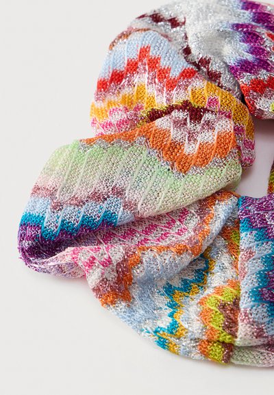 Tissu tricoté multicolore avec des motifs en zigzag et chevrons dans des teintes vives comprenant des fils orange, violet, bleu, vert et argent.