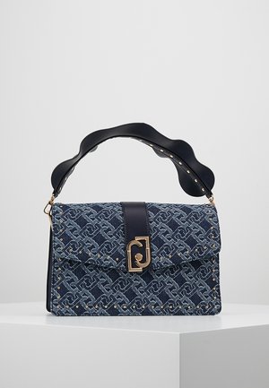 Blå mønstret håndtaske med gyldne nitter, sort bølget håndtag og central gylden lås, vist på en hvid piedestal mod en grå baggrund.