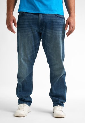 Denim jeans in een donkerblauwe wasservice met een licht vervaagd textuur, rechte snit, vijf-pocket ontwerp, gecombineerd met witte sneakers.