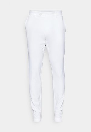 Pantalon blanc ajusté en tissu lisse, avec une taille plate, des poches latérales et des ourlets retournés. Texture subtile et fermeture à bouton.