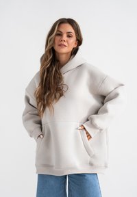 Hellgraue oversized Kapuzenjacke aus weichem Material, mit einer großen Fronttasche, einer Kordelzugkapuze und gerippten Bündchen. Lässiger, bequemer Schnitt.