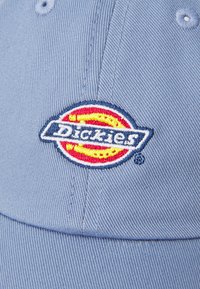 Boné de algodão azul claro com um logotipo bordado redondo em vermelho, amarelo e azul, com o texto "Dickies" em letras brancas em negrito.