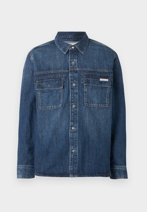 Tumesinist teksast pikkade varrukatega särk, ees nupud, kaks taskut kaelusel, paremal taskul väike Calvin Kleini silt.