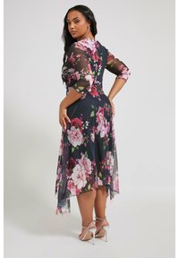 Kukkainen midi-mekko, jossa on läpinäkyvät, pitkät hihat, tummansininen pohja ja vaaleanpunaisia kukkia; se sisältää epäsymmetrisen helmaviivan ja istuvan yläosan.