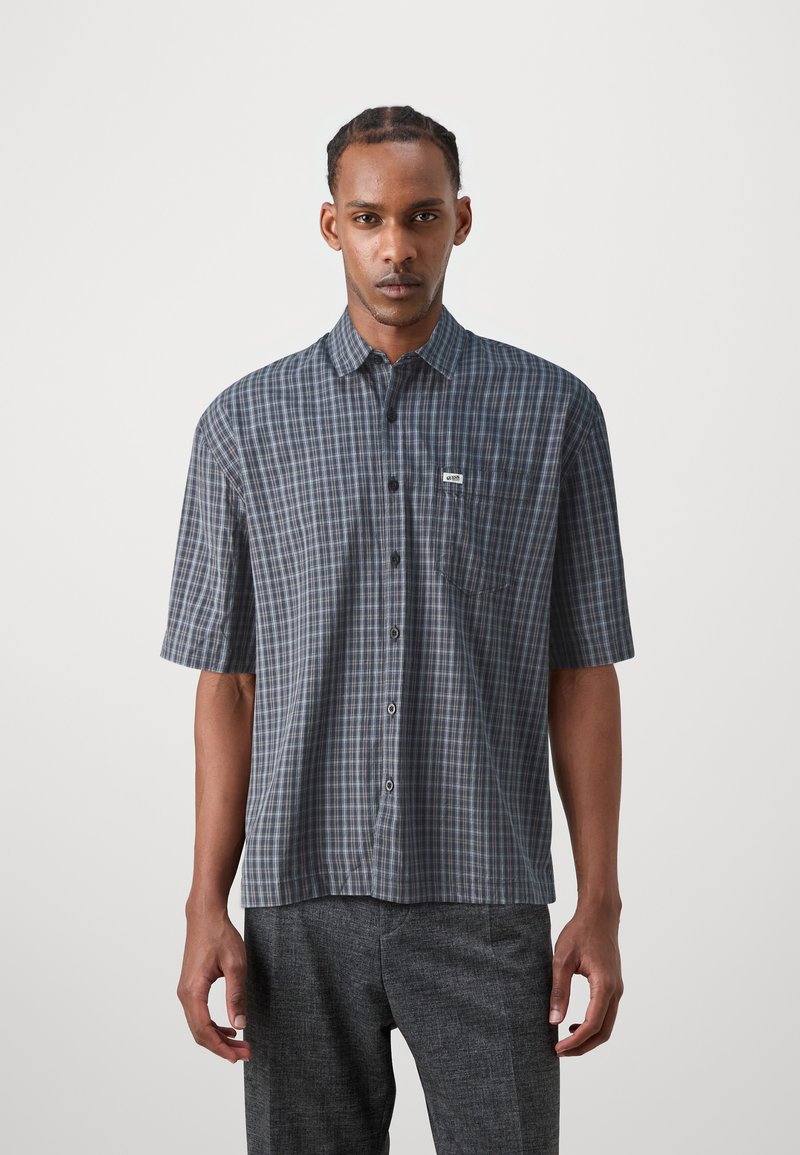 Short-sleeved plaid shirt in navy and grey, featuring a button-down front, a small pocket, and a label on the chest. Smooth fabric texture.