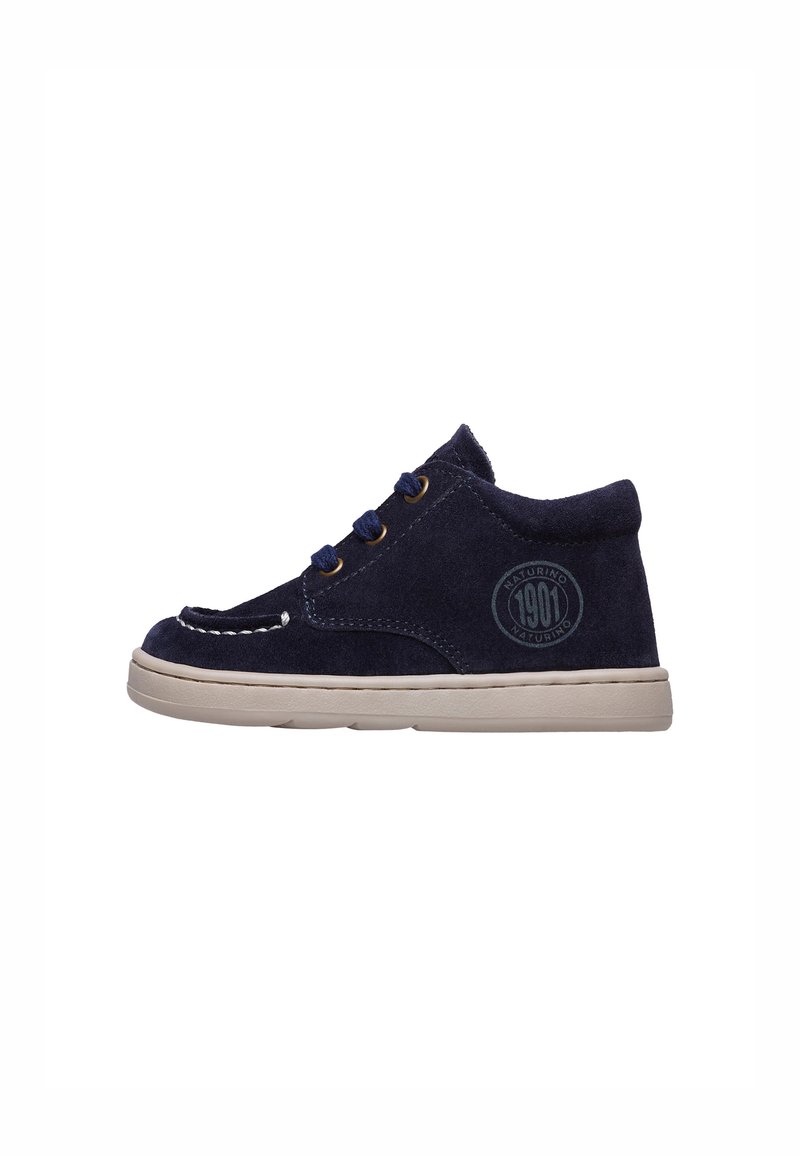 Scarpe alla caviglia in suede blu navy con suola beige, caratterizzate da punta tonda, cuciture decorative e logo sul lato. Lacci in tre asole.