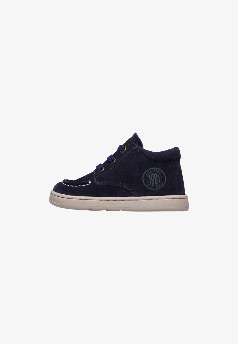 Scarpe alla caviglia in suede blu navy con suola beige, caratterizzate da punta tonda, cuciture decorative e logo sul lato. Lacci in tre asole.