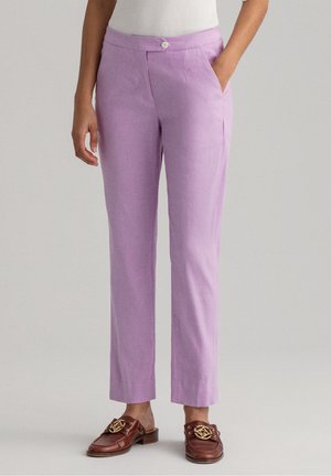 Pantalons en lin violet clair avec une coupe droite, présentant des poches avant et une fermeture à bouton. Portés avec des mocassins marron.