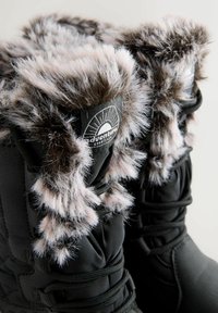 Czarne zimowe buty z grubym szarym i białym futrem sztucznym oraz sznurówkami, z logo "przygoda" na górnej części cholewki.