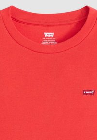 Punainen puuvillapaita, jossa on ribattu pyöreä kaula-aukko. Mukana pieni kudottu Levi's-logo-osa rinnassa. Suunniteltu kevyeksi ja sileäksi kankaaksi.