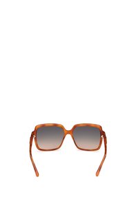 Occhiali da sole quadrati con una montatura traslucida arancio-marrone, lenti grigie sfumate e stanghette sottili con sottili accenti metallici.