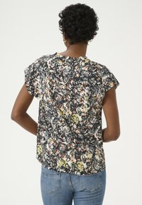 Bluse med kortærmer i let stof med blomstermønster i sort, hvid og farverige nuancer. Lidt løstsiddende pasform med rund halsudskæring.