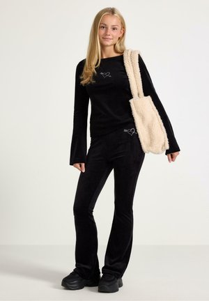 Black velvet long-sleeve top and matching pants with a heart design. Paired with a cream, fluffy fabric shoulder bag and black sneakers.