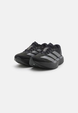 Un paio di scarpe da corsa Adidas Adizero nere con strisce grigie, suole spesse e lacci su uno sfondo bianco.