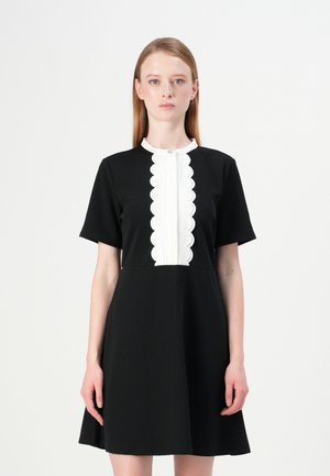 Zwarte jurk met korte mouwen en een witte geschulpte placket. A-lijnvorm met een gladde, gestructureerde afwerking. Knopdetail bij de halslijn.
