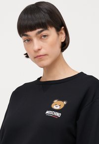 Svart sweatshirt med et bjørnegraphikk på brystet. Laget av en bomullsblanding, har den rund hals og ribbestrikkede mansjetter.