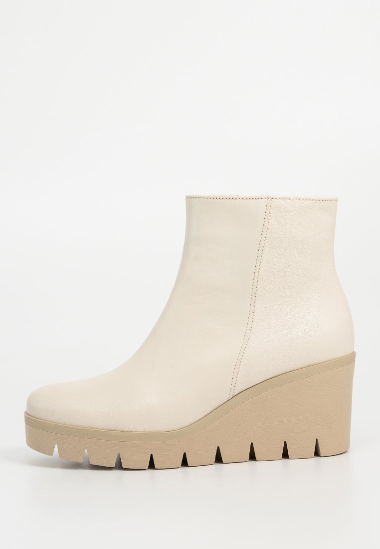 Beige leren enkellaars met verstelbare hak en geribbelde rubberen zool, zijaanzicht op een witte achtergrond.