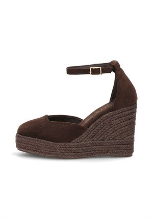 Alpargata de cuña de ante marrón con correa en el tobillo y hebilla dorada, suela de cuerda trenzada, puntera cerrada y redondeada, vista lateral sobre fondo blanco.