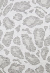 Harmaa leopardikuvioinen kangas, jossa on pehmeä tekstuuri ja epäsäännölliset täplät valkoisella pohjalla, korostaen sileää, neulottua kuviota.