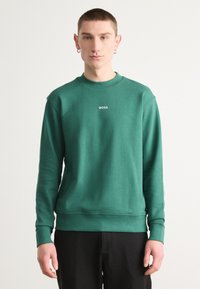 Sudadera de algodón verde con mangas largas, cuello redondo y puños acanalados. Presenta el logo 'BOSS' en blanco en el pecho, con una textura suave.