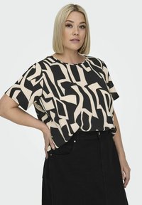 Short-sleeve top featuring a black and beige abstract pattern. Made from lightweight fabric with a relaxed fit and a round neckline.