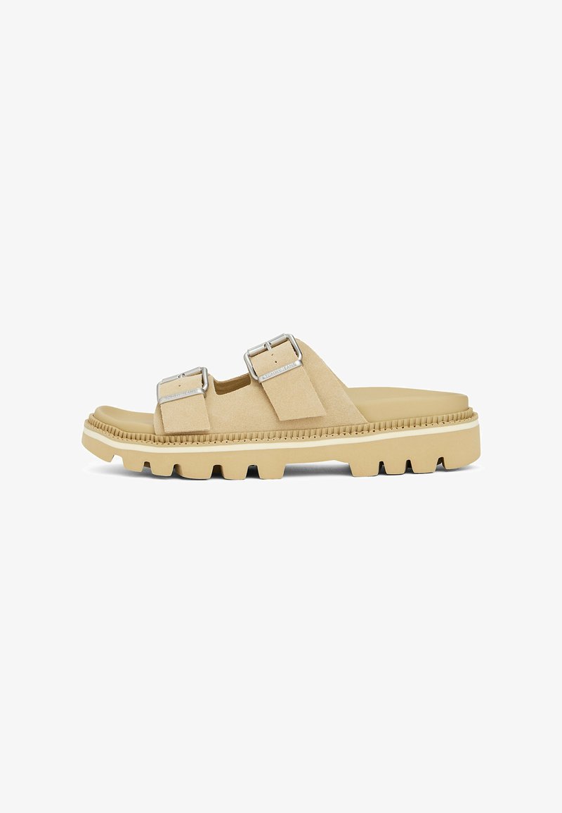 Sandalias deslizantes de ante beige con dos correas ajustables, hebillas de plata y una suela de goma gruesa y texturizada que cuenta con profundos surcos para mayor tracción.