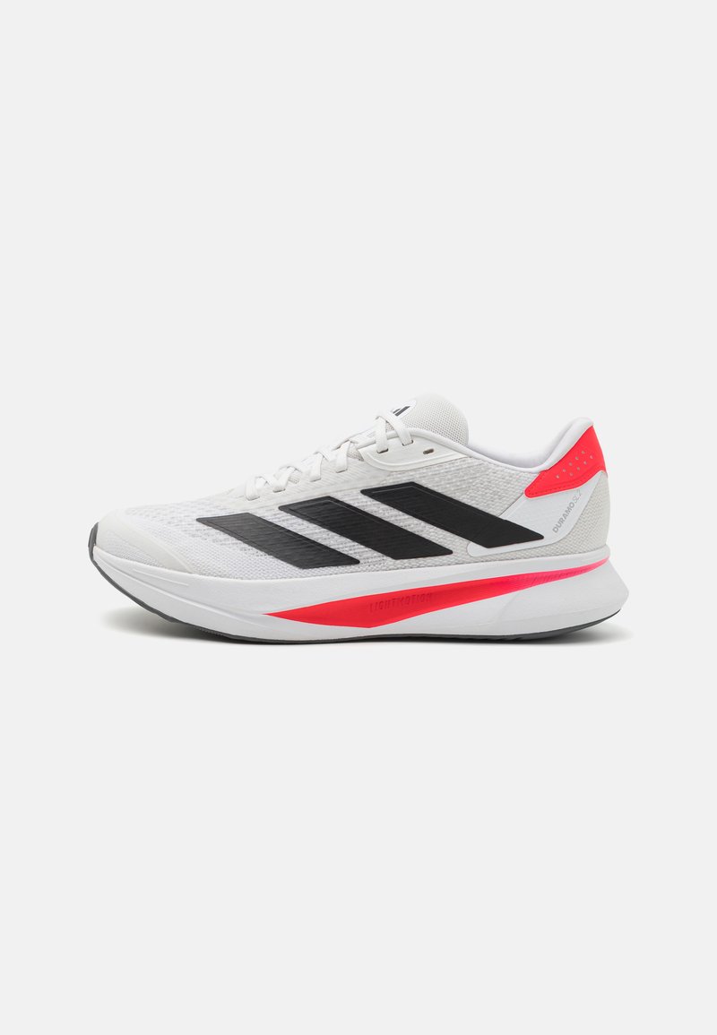 Baskets blanches de sport avec des rayures noires, un dessus texturé, des accents roses et une semelle légère portant le logo "LIGHTMOTION".