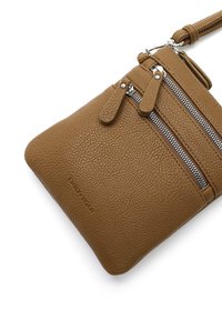 Hnědá kožená crossbody taška s texturovaným povrchem, která má více zipových kapes, stříbrné kovové detaily a odnímatelný popruh.