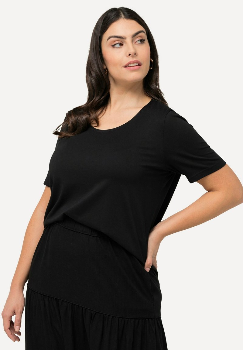 T-shirt nero a maniche corte, scollo rotondo, tessuto morbido, vestibilità ampia, abbinato a una gonna nera a ruota, texture liscia, dettaglio di drappeggio sottile.