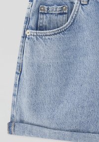 Short en denim bleu clair avec poche avant, petite poche à monnaie, rivets argentés et ourlet roulé en bas.