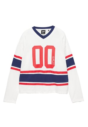 Cămașă albă cu mâneci lungi și decolteu în V, având dungi roșii și bleumarin și numărul „00” în roșu îndrăzneț. Material moale din bumbac.